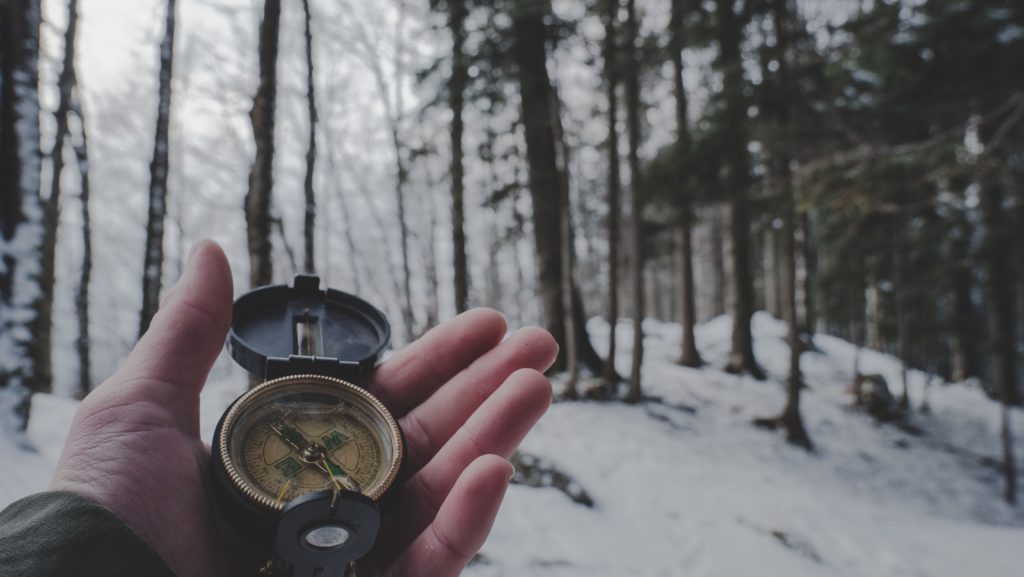 Man holding compass in the woods